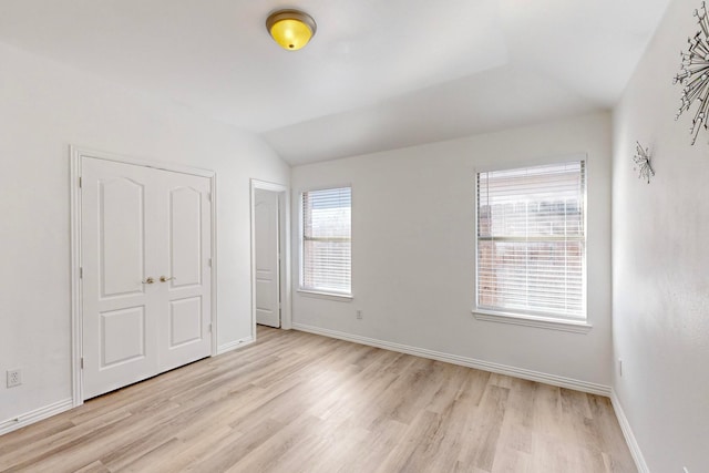 unfurnished bedroom with vaulted ceiling and light hardwood / wood-style flooring