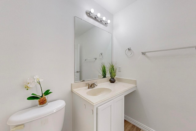 bathroom featuring toilet, vanity, and hardwood / wood-style floors