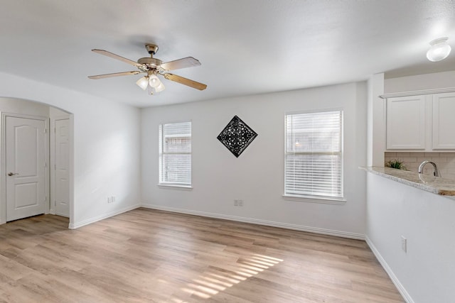 empty room featuring plenty of natural light, ceiling fan, and light hardwood / wood-style flooring