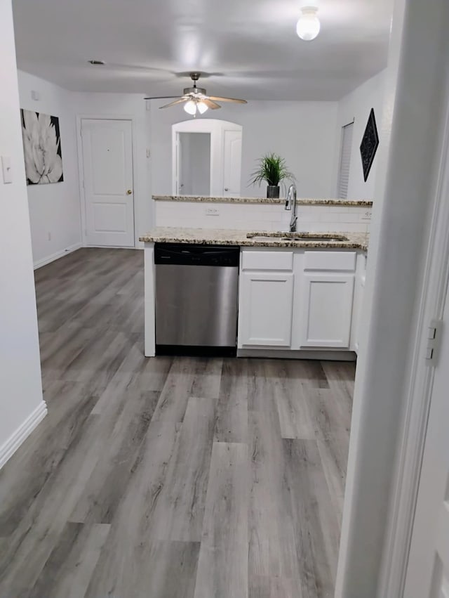 kitchen with sink, light stone countertops, stainless steel dishwasher, white cabinets, and light wood-type flooring