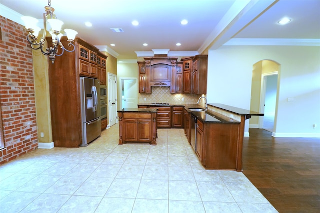 kitchen with sink, kitchen peninsula, a kitchen island, stainless steel appliances, and crown molding