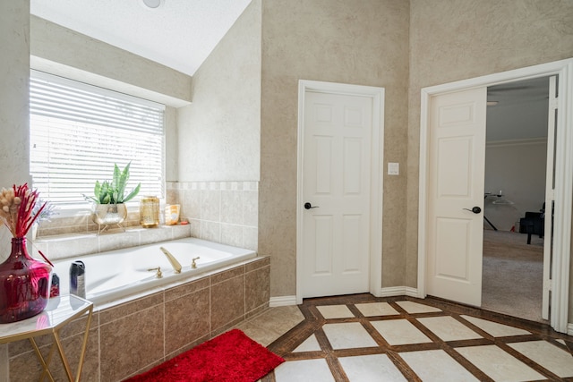 bathroom featuring tiled tub and vaulted ceiling