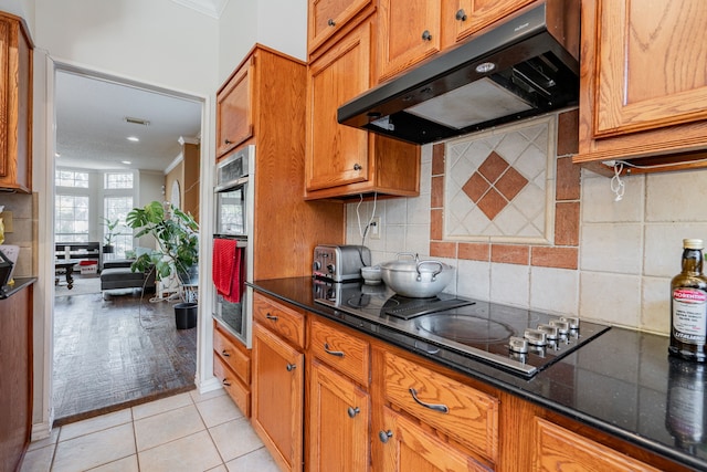 kitchen featuring range hood, ornamental molding, light tile patterned floors, and stainless steel double oven