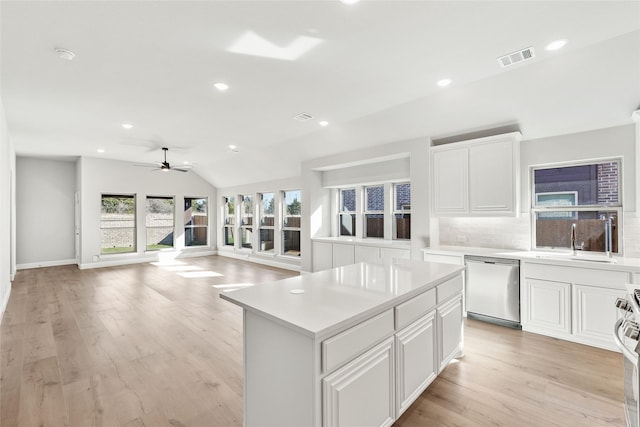 kitchen with white cabinets, stainless steel dishwasher, decorative backsplash, and a center island