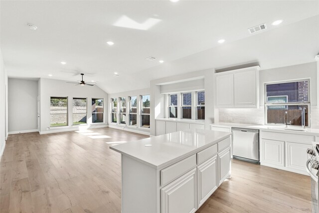 kitchen with white cabinets, stainless steel dishwasher, decorative backsplash, and a center island