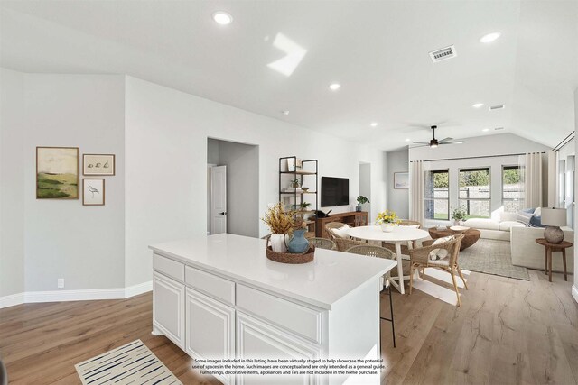 kitchen featuring vaulted ceiling, light hardwood / wood-style floors, a kitchen island, white cabinetry, and ceiling fan