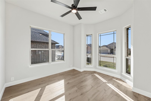 empty room featuring ceiling fan, plenty of natural light, and light hardwood / wood-style flooring