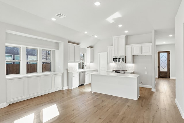 kitchen with sink, white cabinetry, a center island, decorative backsplash, and appliances with stainless steel finishes