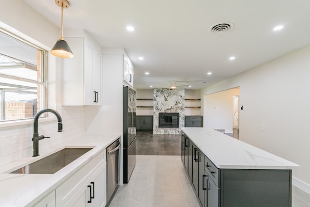 kitchen with light stone counters, hanging light fixtures, sink, and white cabinets