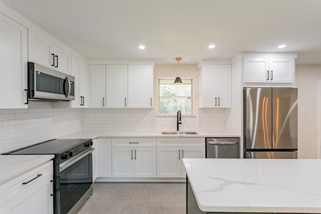 kitchen featuring stainless steel appliances, decorative light fixtures, sink, and white cabinetry