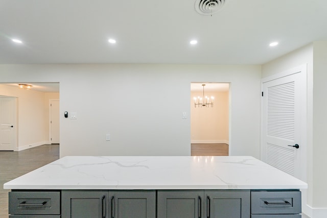 kitchen with light stone counters, a center island, pendant lighting, a chandelier, and gray cabinets