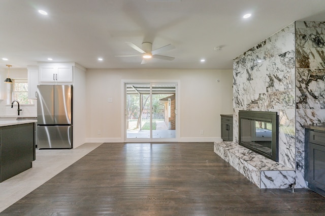 unfurnished living room featuring a premium fireplace, hardwood / wood-style flooring, and ceiling fan