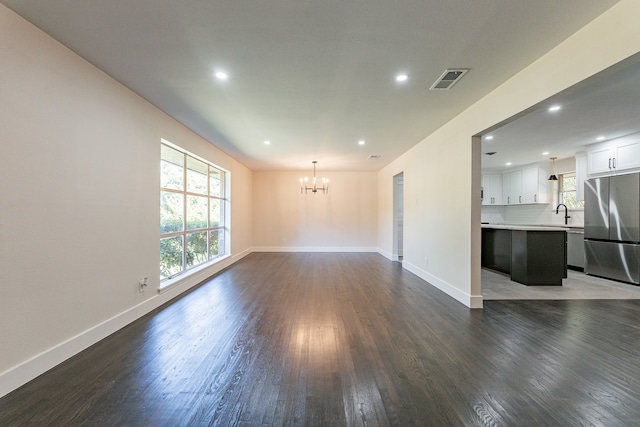 unfurnished living room featuring a chandelier, dark hardwood / wood-style flooring, and sink