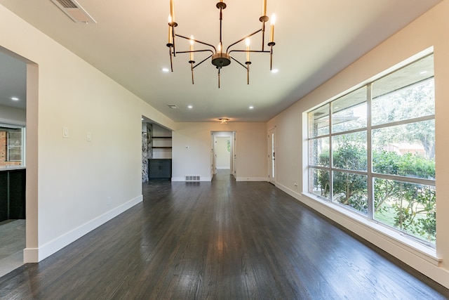 unfurnished living room with an inviting chandelier, dark hardwood / wood-style floors, and a healthy amount of sunlight