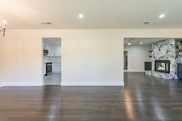 unfurnished living room featuring dark hardwood / wood-style floors and a stone fireplace