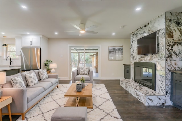 living room with wood-type flooring, a premium fireplace, a wealth of natural light, and ceiling fan