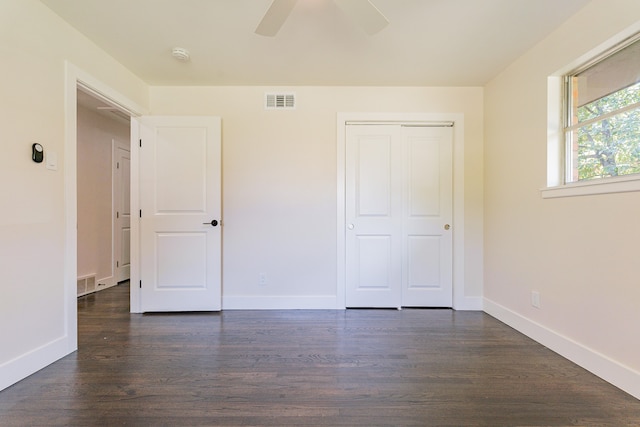 unfurnished bedroom with ceiling fan, dark wood-type flooring, and a closet