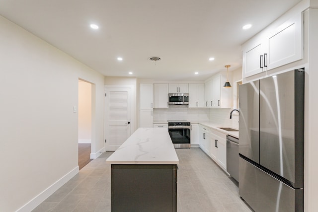 kitchen featuring stainless steel appliances, hanging light fixtures, a center island, and white cabinetry