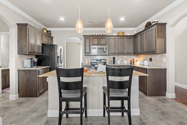 kitchen with dark brown cabinets, pendant lighting, stainless steel appliances, and crown molding