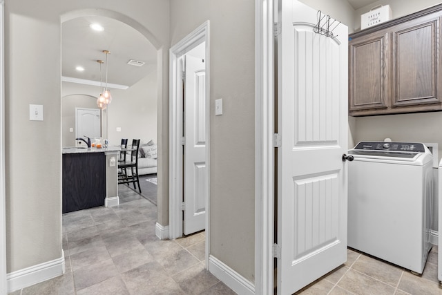 clothes washing area featuring washer / dryer, crown molding, and cabinets