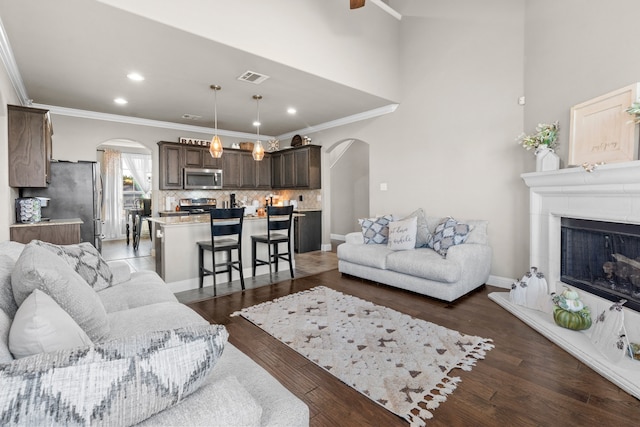 living room with dark hardwood / wood-style floors, ornamental molding, and ceiling fan