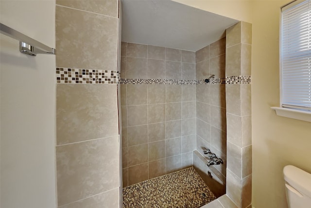 bathroom with a tile shower and toilet