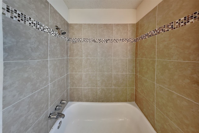 bathroom featuring tiled shower / bath and a textured ceiling