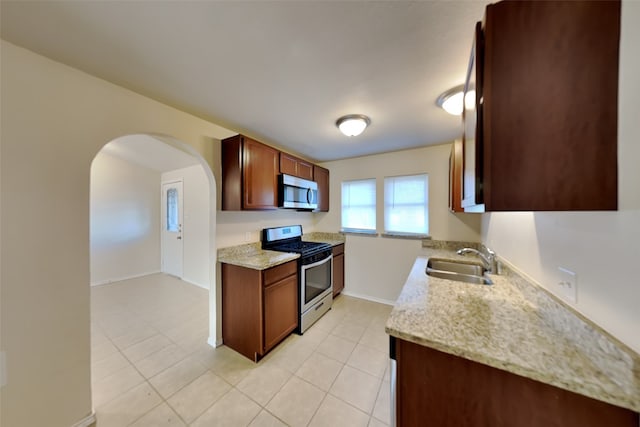 kitchen featuring appliances with stainless steel finishes, light stone countertops, sink, and light tile patterned floors