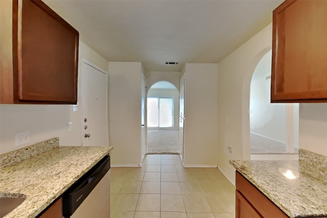 kitchen with light stone countertops, light tile patterned floors, and dishwasher