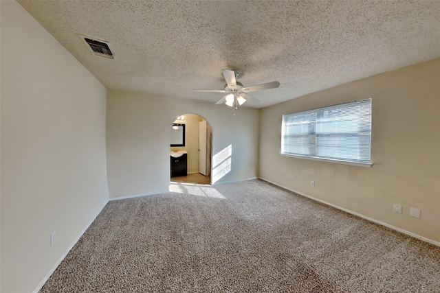 unfurnished room with light carpet, ceiling fan, and a textured ceiling