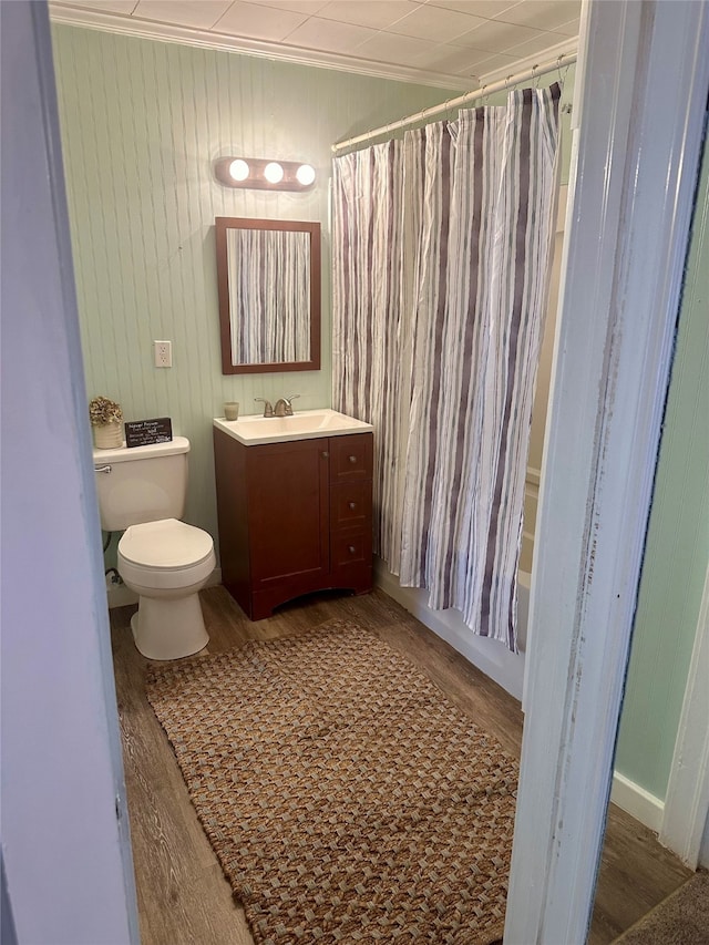 full bathroom featuring hardwood / wood-style flooring, toilet, shower / bath combo with shower curtain, ornamental molding, and vanity