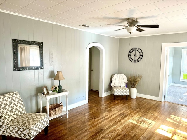 living area featuring wood walls, wood-type flooring, and ornamental molding