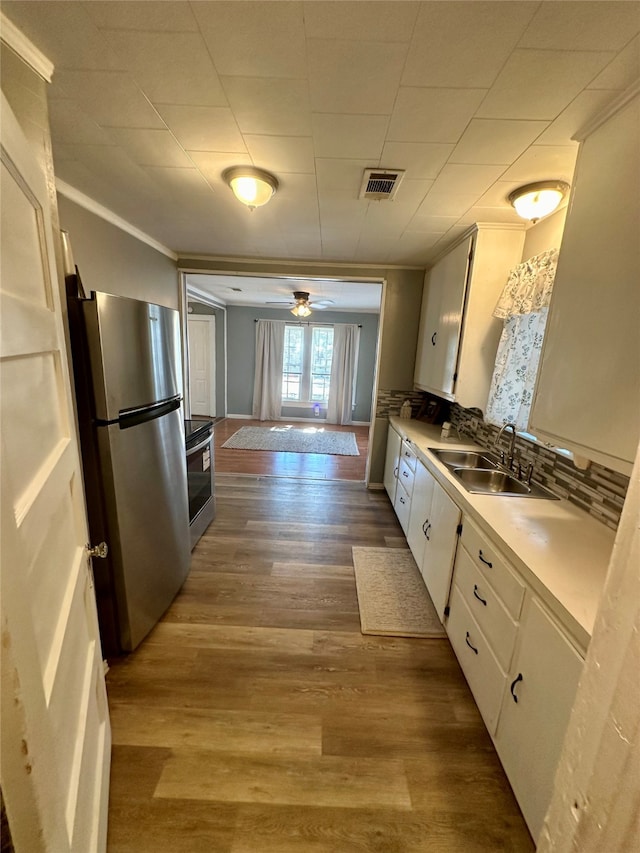 kitchen with stainless steel appliances, sink, white cabinets, light hardwood / wood-style floors, and ceiling fan