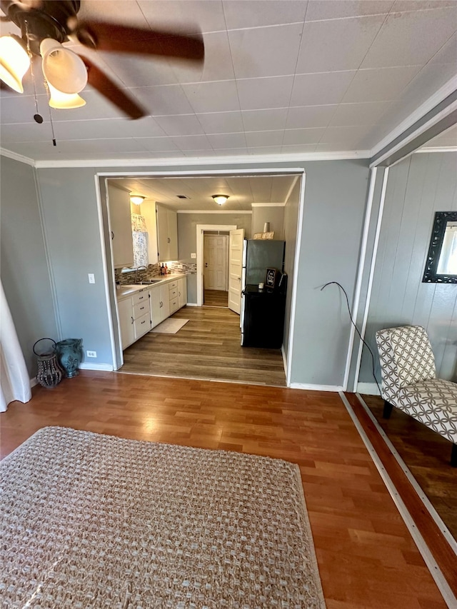 unfurnished living room with hardwood / wood-style floors, crown molding, and ceiling fan