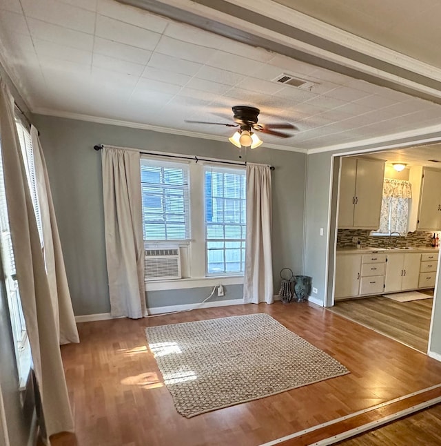 interior space featuring crown molding, light hardwood / wood-style flooring, cooling unit, and ceiling fan