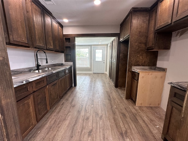 kitchen with dark brown cabinets, light hardwood / wood-style floors, and sink