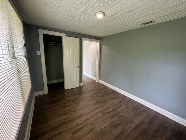 unfurnished bedroom featuring a closet, dark hardwood / wood-style floors, and wood ceiling