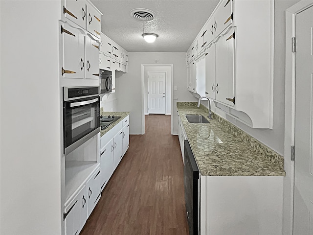 kitchen with stainless steel oven, sink, dark hardwood / wood-style floors, white cabinets, and a textured ceiling