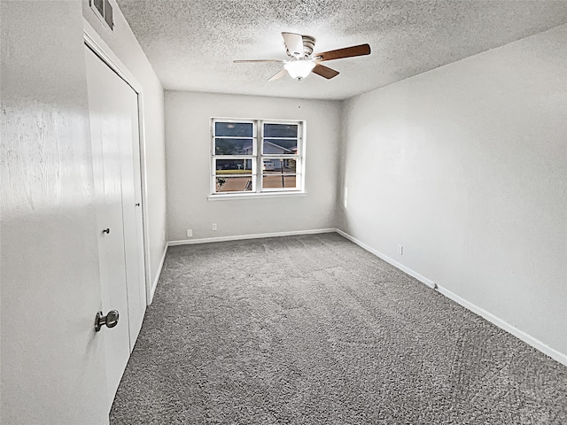 empty room featuring ceiling fan, carpet, and a textured ceiling