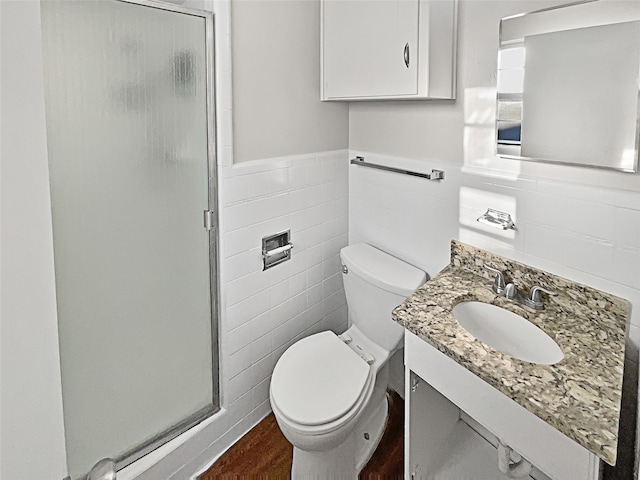 bathroom with vanity, a shower with door, toilet, and tile walls