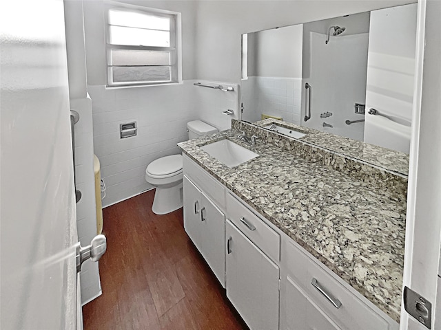 bathroom featuring vanity, toilet, walk in shower, tile walls, and hardwood / wood-style floors