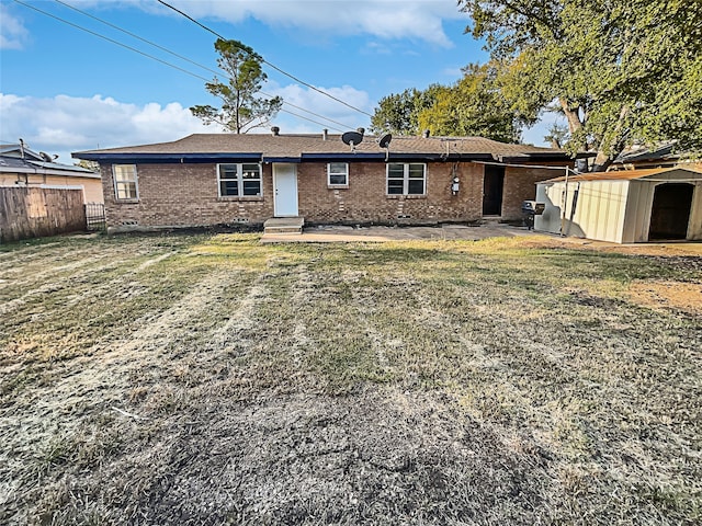 rear view of property featuring a yard, a storage shed, and a patio area