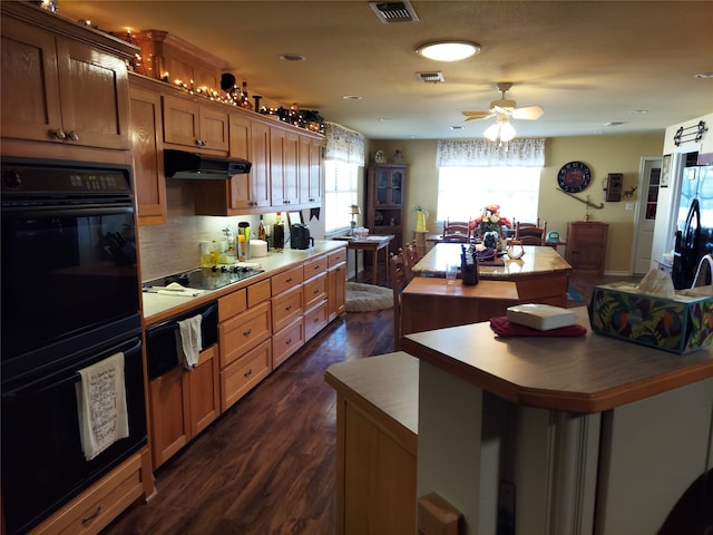 kitchen with decorative backsplash, ceiling fan, dark hardwood / wood-style flooring, black appliances, and a center island