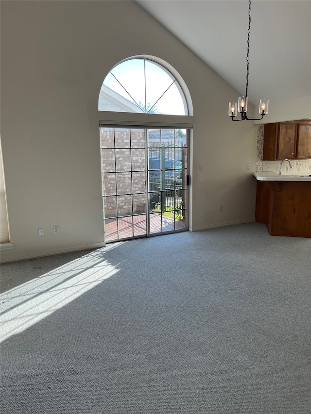 empty room with sink, high vaulted ceiling, an inviting chandelier, and light carpet