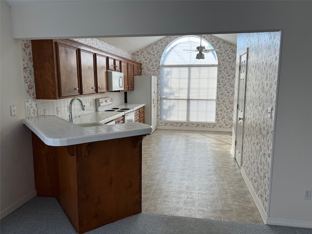 kitchen featuring ceiling fan, white appliances, sink, tile counters, and kitchen peninsula