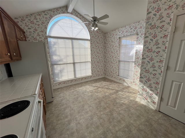 interior space with ceiling fan, vaulted ceiling with beams, tile countertops, and white electric stove