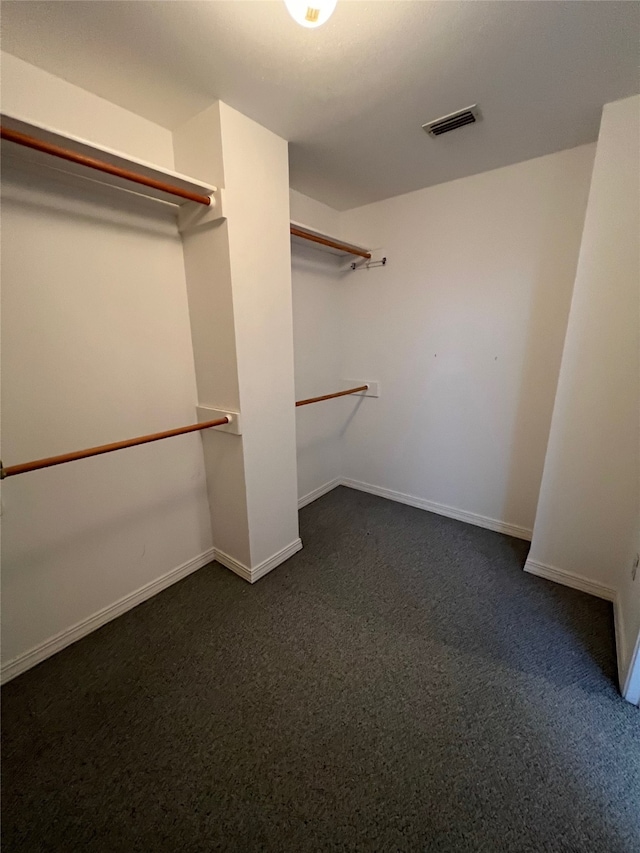 walk in closet featuring dark colored carpet