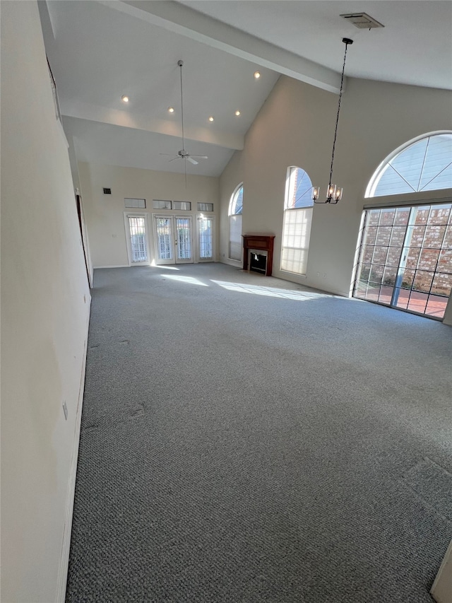 unfurnished living room featuring high vaulted ceiling, ceiling fan, beamed ceiling, and carpet flooring