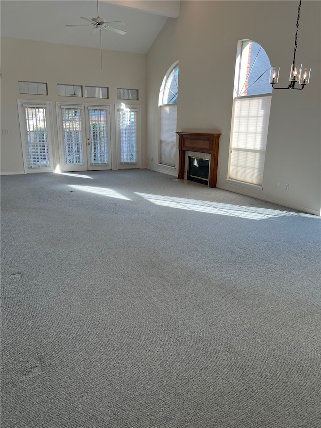 unfurnished living room featuring high vaulted ceiling, plenty of natural light, and carpet floors