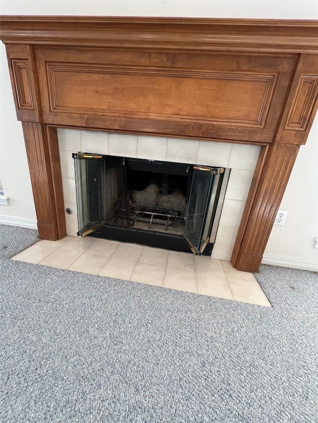 interior details featuring carpet and a tiled fireplace